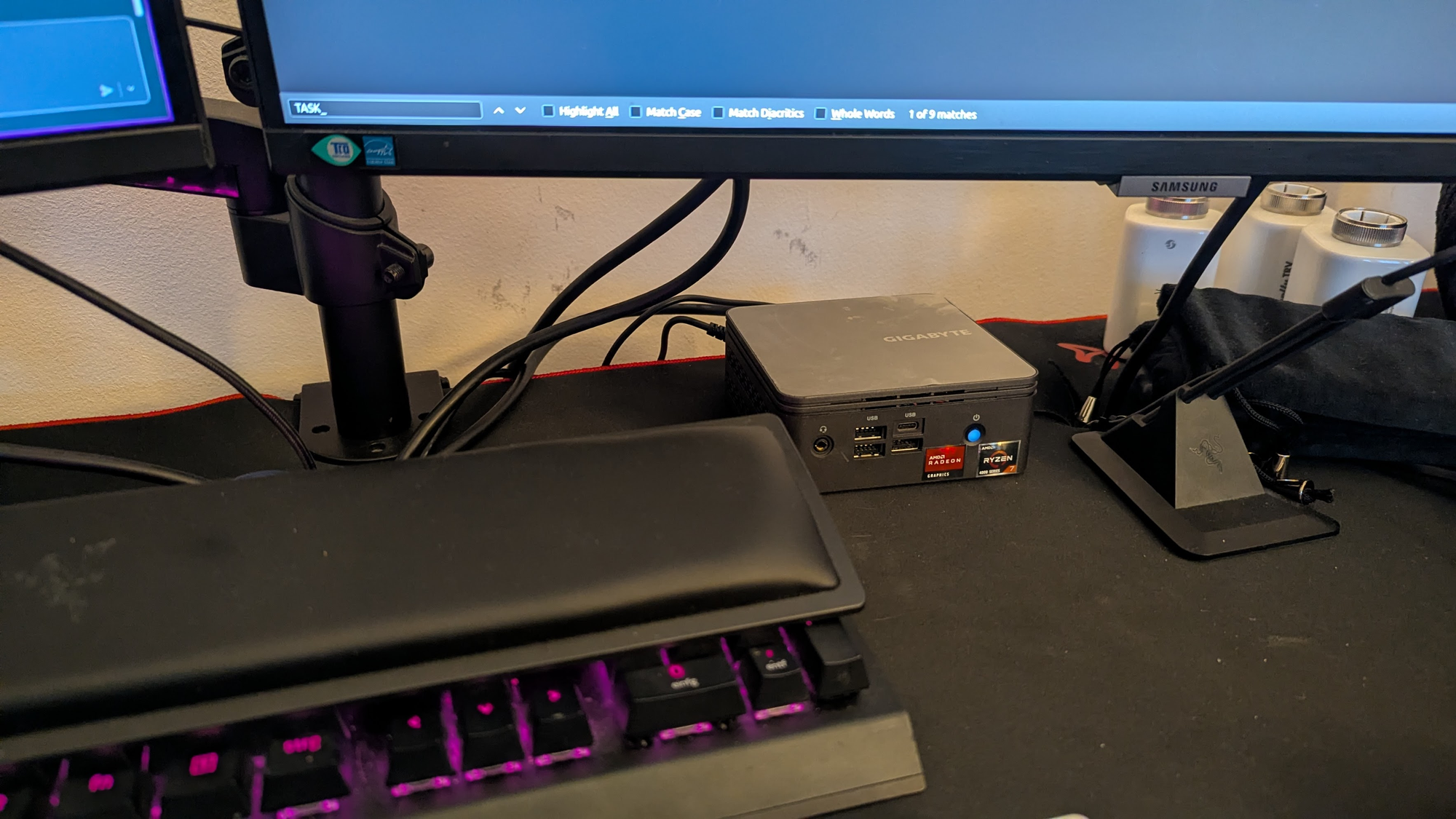 A picture of a NUC on my desk, snuggly fitting under one of the monitors.